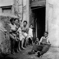 A family sits outside the front door of their District Six home